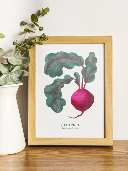 Framed artwork of a beet with lush green leaves on a wooden surface.