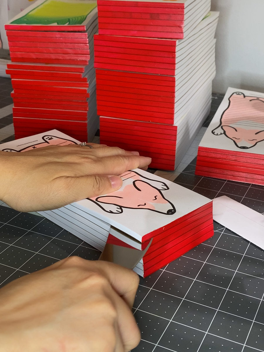 Slicing apart glued risograph notepads during the assembly process.